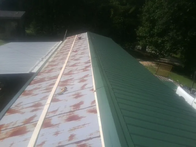 Old rusted panels beside newly installed green metal roofing — Wind Damage Roof Repair by Roofing Brothers in Hesperia