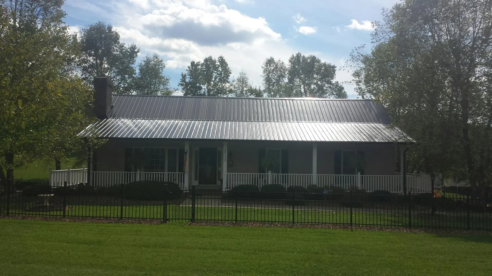 Gray metal roof on a brick ranch with a full width front porch — Gutter Guard Installation work by our crew in Hesperia