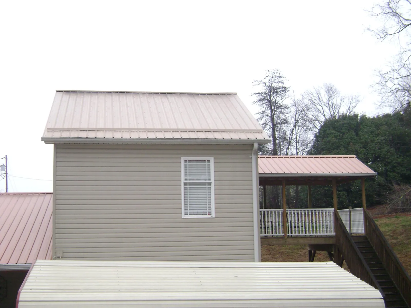 Tan metal roofs on a two story addition and attached porch, from a Roof Replacement job in Hesperia